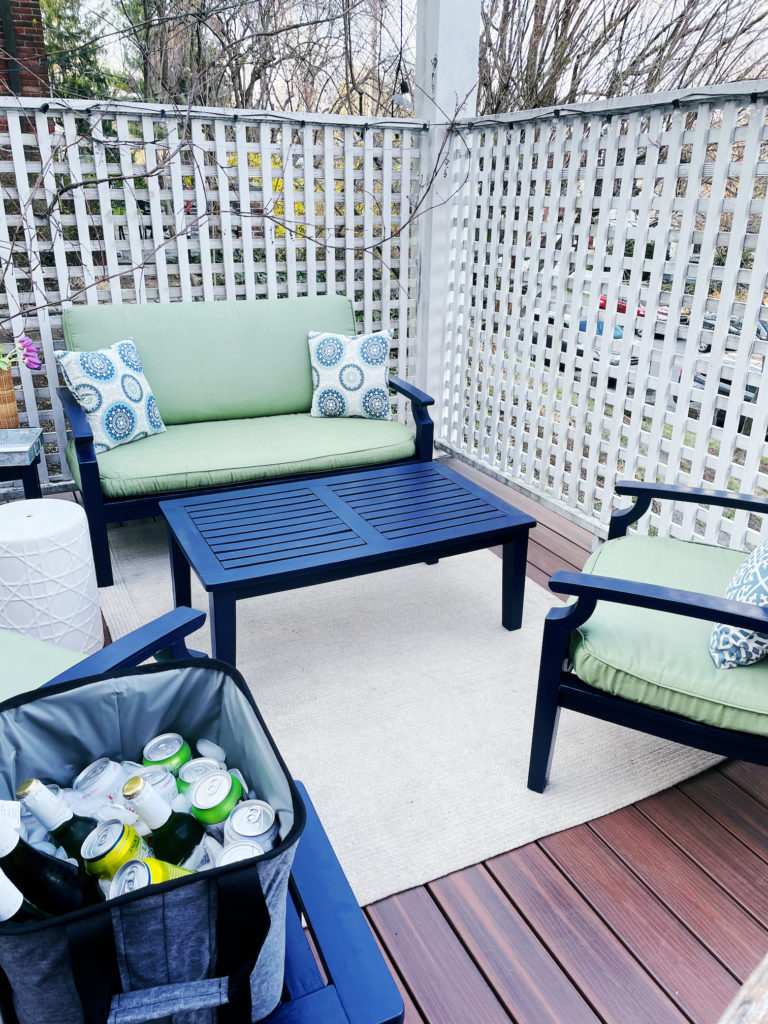 A deck with blue furniture and a cooler with drinks